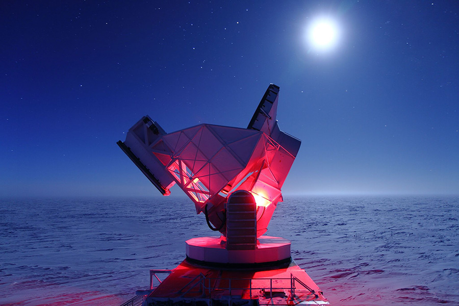 Photo shows part of the telescope lit in red on a moonlit night, with snow visible all the way to the horizon.