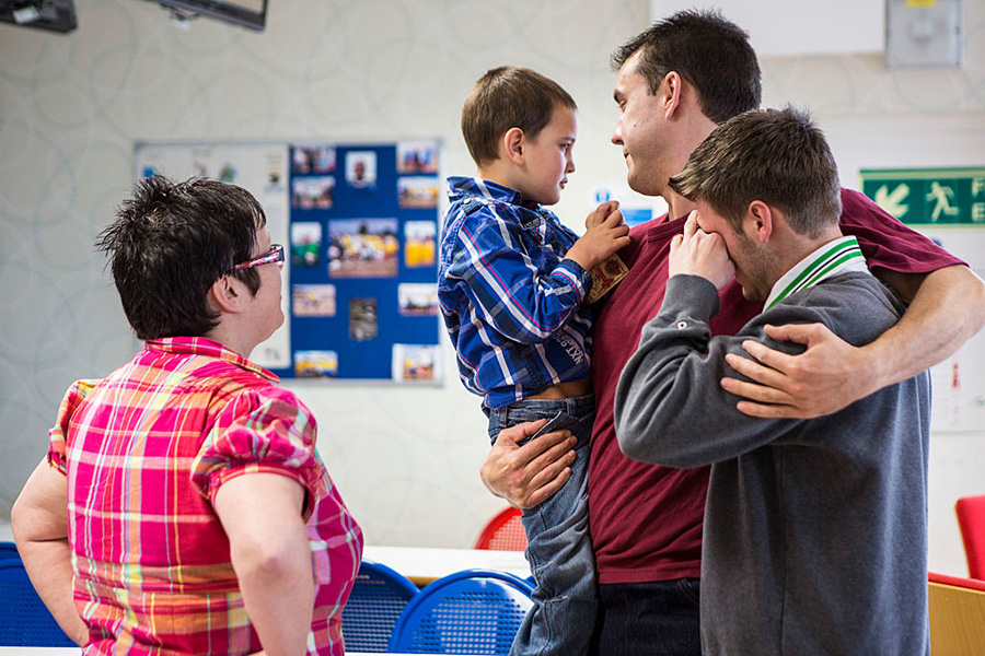 A prisoner holds his children during a family visit.