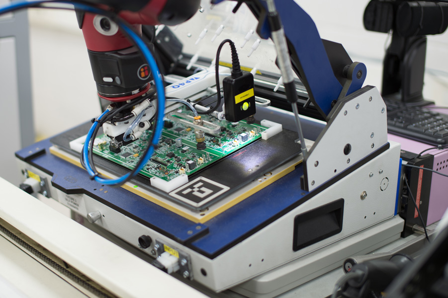 La photo montre un travail précis effectué par un cobot dans la fabrication d'une carte de circuit imprimé.