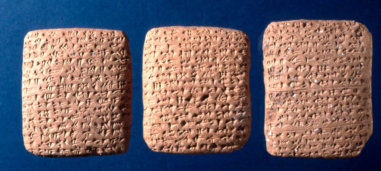 Photograph of three clay tablets covered with                cuneiform lettering.