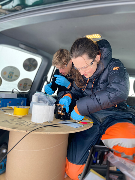 Researchers Sara Klaasen and Andreas Fichtner splice optical fibers in the back of a vehicle atop an Icelandic glacier. It is tricky work for cold hands in a harsh environment.