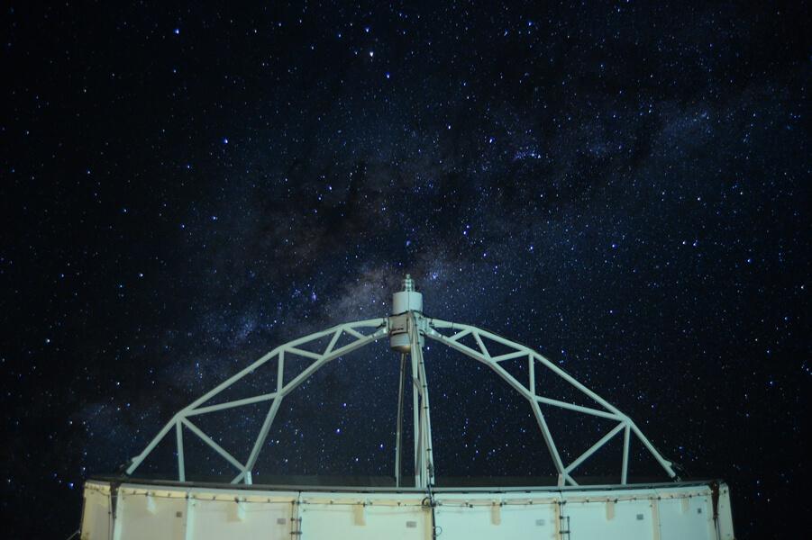 Photo shows the dish of the APEX telescope directed toward the night sky.