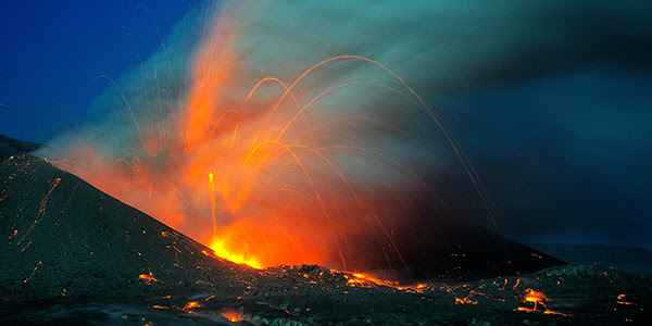 Photo shows orange lava spewing from atop a volcanic crater.