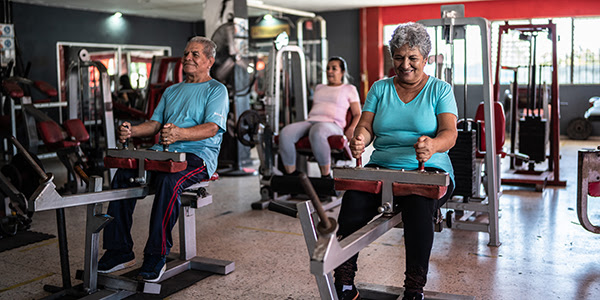 Photograph older adults working out in a gym on exercise machines.