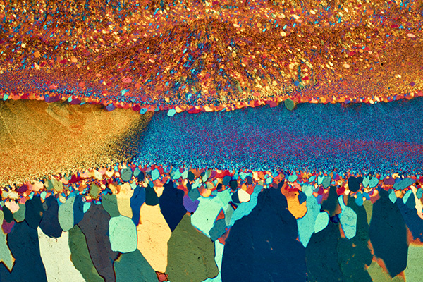 a close-up photo shows a large band of speckled orange above two wide streaks of yellow and blue above multi-colored chunks.