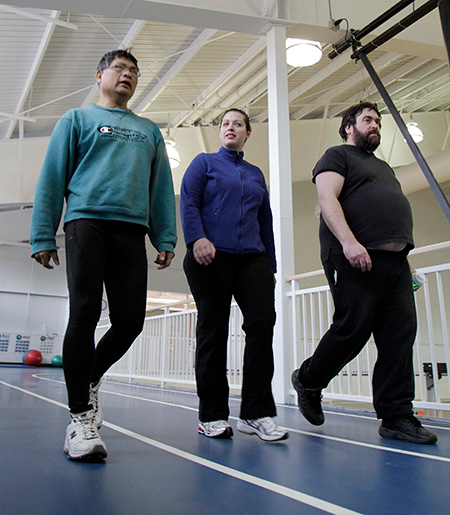 Three people in workout clothes walk along an indoor athletic track.