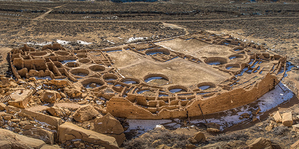 Aerial view of Pueblo Bonito, in Chaco Canyon, New Mexico. The site has a semicircular shape with clusters of rectangular rooms . Pueblo Bonito has more than 600 rooms arranged on multistory levels. These rooms enclose a central plaza.