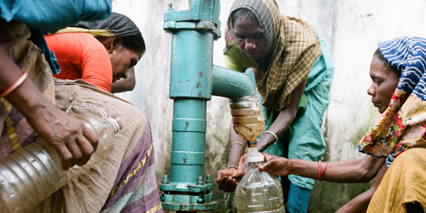 Photo shows women gathered around a shared pump to collect drinking water in Srimongol, Bangladesh.