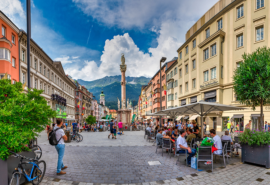 People sit at tables in a busy square in Innsbruck, Austria, in 2019.
