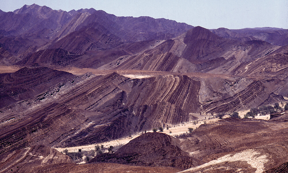 Paul Hoffman has spent a cumulative 50 months collecting evidence of Snowball Earth in the desert mountain ranges of Namibia, shown in a photograph. The landscape in the photo is comprised of an ancient seafloor punctuated with so-called dropstones — sporadically placed stones that researchers believe were carried by ice floating out at sea.