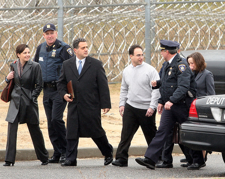 A man in a white sweater leaving jail after his release, accompanied by several others.