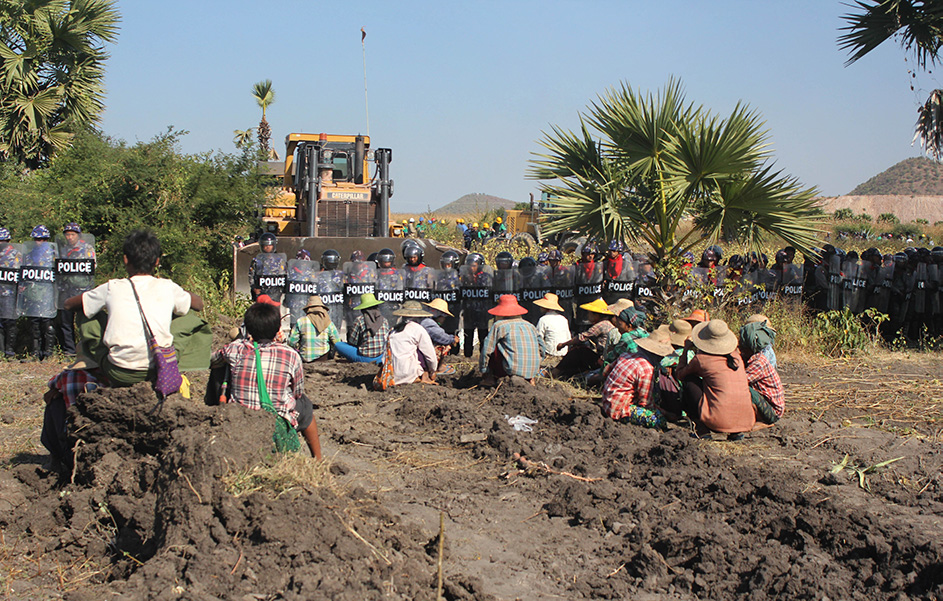 Photograph of local people facing a bulldozer and riot police as they protest a copper mine.