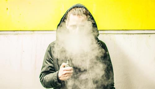 Young person in a hoodie sweatshirt vaping