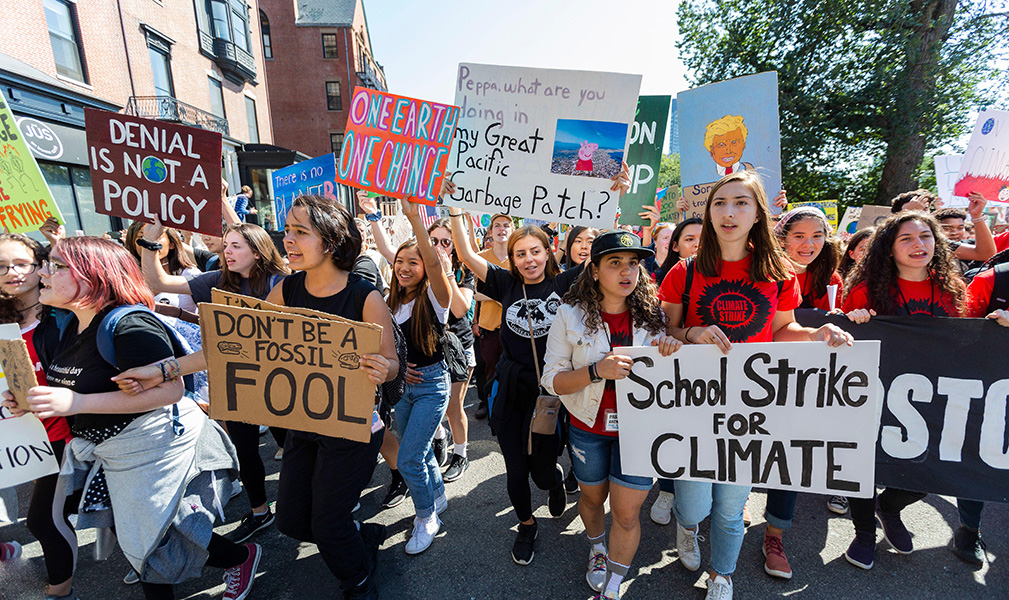 Photograph of teenagers demonstrating in the streets. They are holding banners with slogans such as “One Earth, one chance,” “Don’t be a fossil fool” and “School strike for climate.”