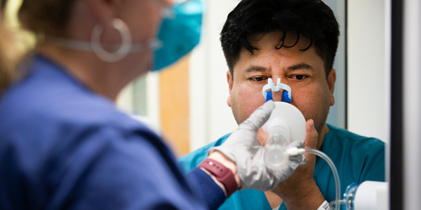 A patient breaths in through a breathing apparatus during a medical test