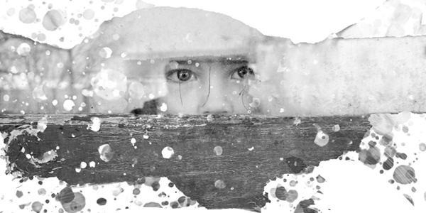 The eyes of a child are seen looking fearfully through a window.