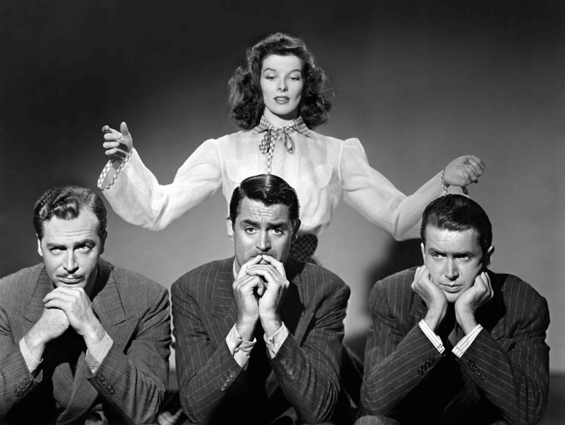 A promotional photo from the 1940s film the Philadelphia Story shows star Katharine Hepburn standing over three men who play her potential beaus in the film.