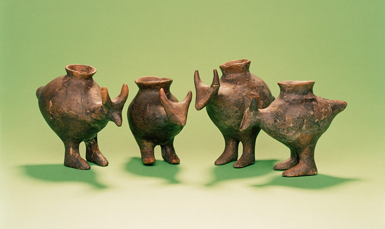 Photo shows four ceramic vessels each with an opening on top and shaped in the form of an animal with a head, ears, two legs and a tail.