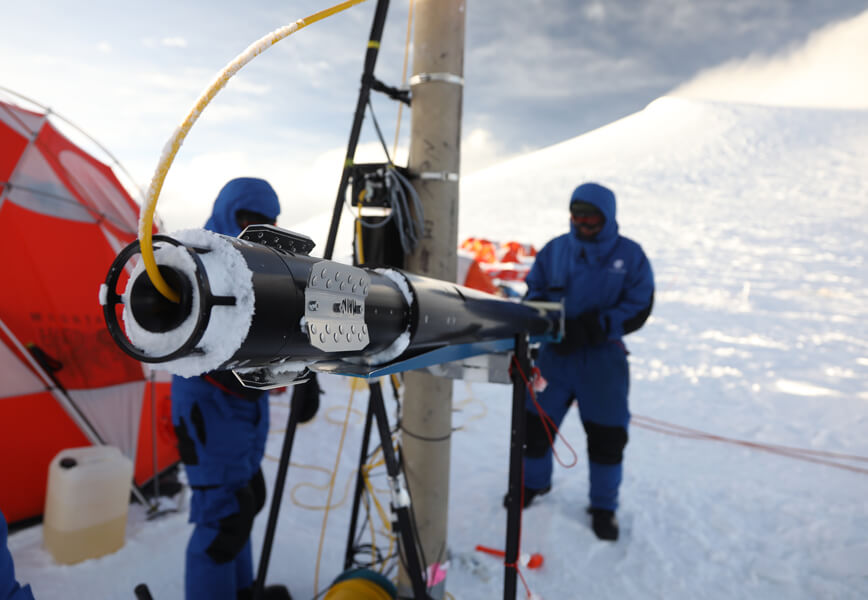 Photo shows scientists drilling into the glacier at a summit camp.