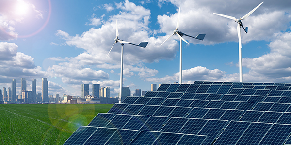 Realistic illustration shows a cityscape with a mix of buildings of different heights; in the foreground is a grid of solar panels and several wind turbines. The sky is blue and filled with fluffy clo