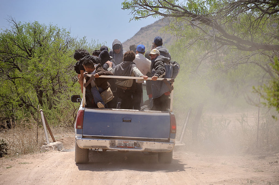 Photo: A pickup truck with many people in the back drives through the desert.
