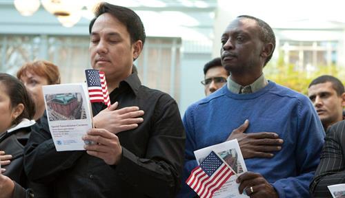 Group of people standing with hands over hearts and holding American flags