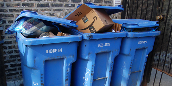 Blue recycle bins are on street and full of recylcing.