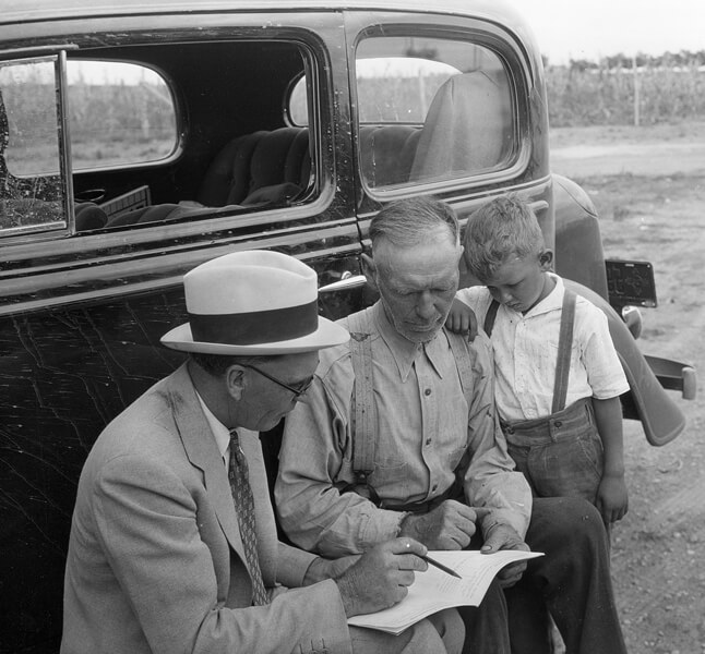 Photo shows a New Mexico farmer reviewing details of original US Farm Bill with county agriculture official, 1934.