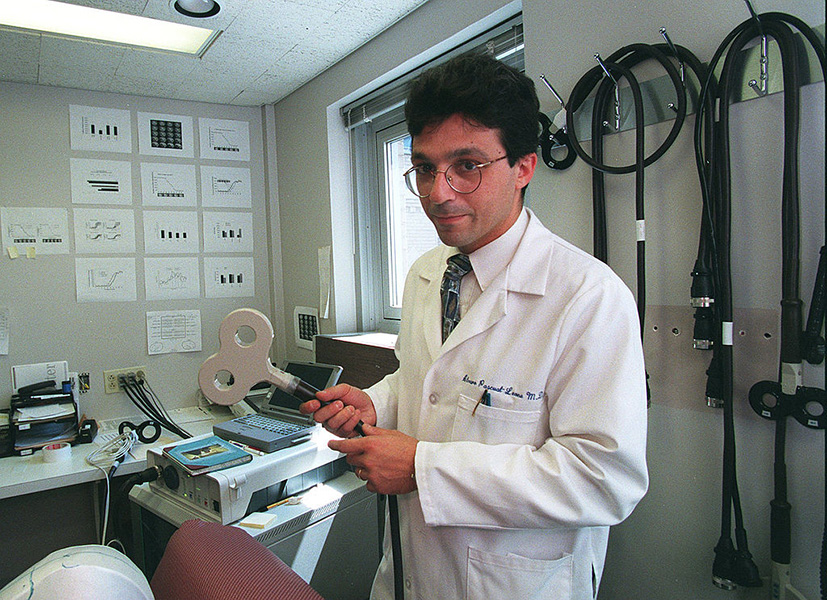 Photograph of neuroscientist Alvaro Pascual-Leone, a pioneer of TMS treatment, holding an early TMS device in the 1990s.