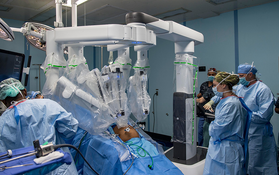 A surgical team watches as a robot manipulates surgical tools inserted in a patient’s abdomen during laparoscopic surgery.