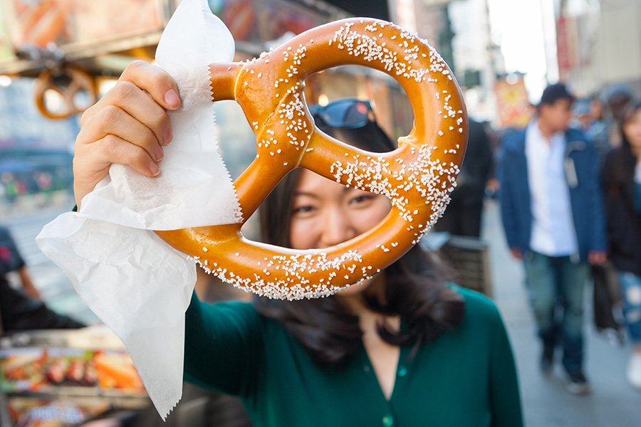 A person holds a large, salty pretzel up to the camera.