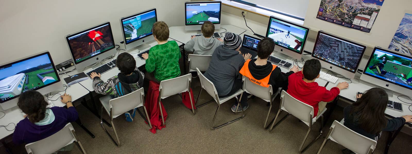 Photo shows a class of students sitting in front of monitors playing a game.