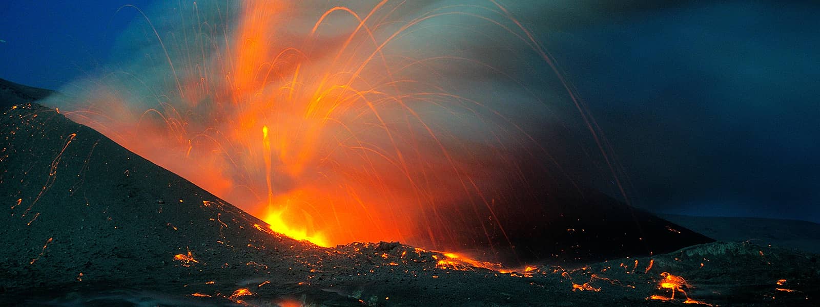 Photo shows orange lava spewing from atop a volcanic crater.