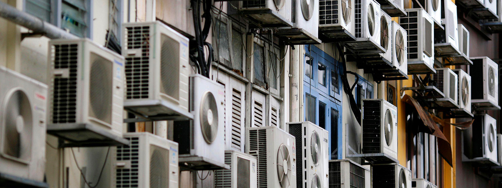 Photograph of dozens of air conditioners on the side of a building.