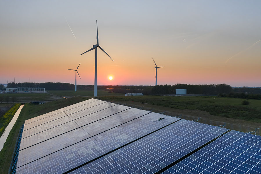 A 2019 photo shows a number of energy-producing wind turbines and solar panels on fields near Waalwijk, Netherlands, during sunset.