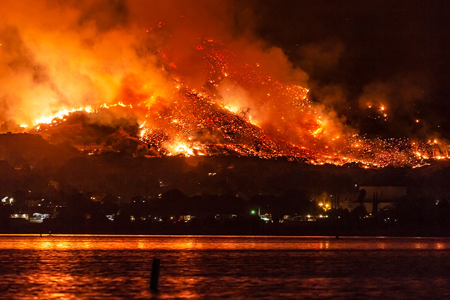 Photo shows the Holy Fire sending embers into the night sky above Lake Elsinore, California in 2018.