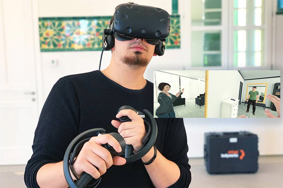 A young man wears a virtual reality headset and two hand controllers.
