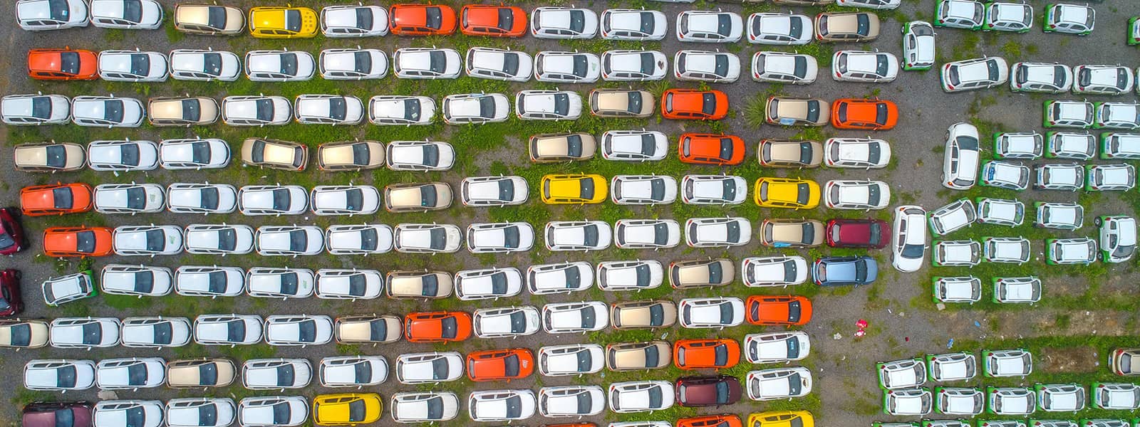 Aerial view of a parking lot crammed with electric cars colored white, tan, yellow and red.