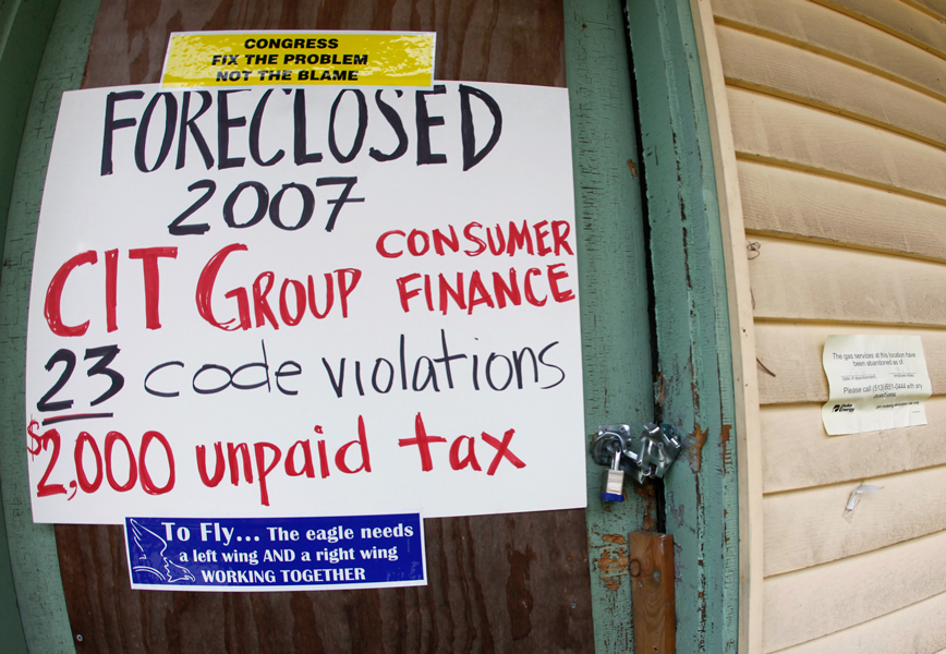 A sign placed by members of Occupy Cincinnati hangs on a locked front door of an unoccupied house in the East Price Hill neighborhood during a demonstration to protest home foreclosures in Cincinnati, Ohio, March 24, 2012. The sign says that the house was foreclosed in 2007 and includes activist bumper stickers.