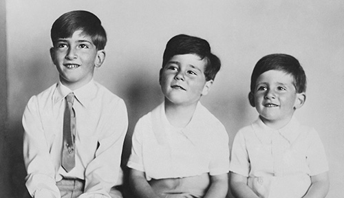 Three young brothers seated side by side, showing family resemblance.