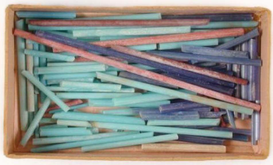 Photograph of a tray filled with blue, red and turquoise glass rods.