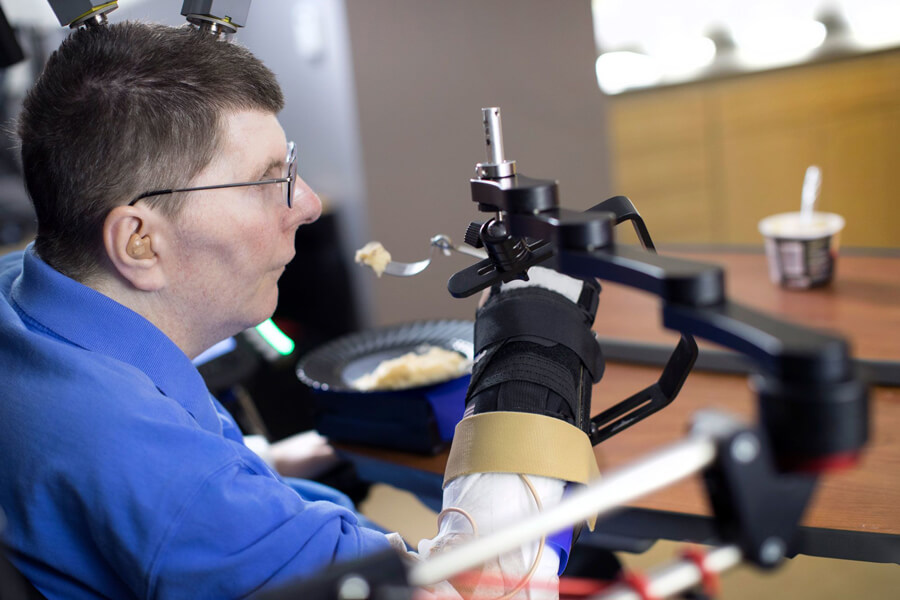 Photograph of Bill Kochevar using his own arm to feed himself a spoonful of mashed potato eight years after he lost use of his arms and legs in a bicycle accident. The setup of electrodes implanted in his brain’s motor cortex, a brain-computer interface and a system to stimulate his arm and hand muscles also allowed him to do simple but important things such as scratch an itch on his nose. Brain instructions also help to control a support device. Researchers say the temporary system could soon be adapted for long-term use.