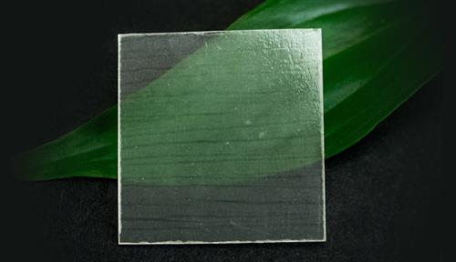 A square piece of clear wood, with a green leaf behind it