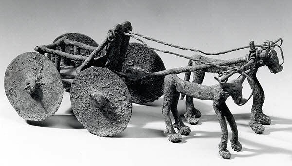 A copper statue of a wagon drawn by bulls.