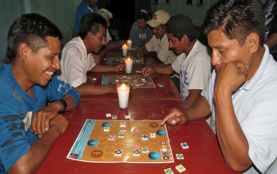 Men sit at a row of tables playing a board game