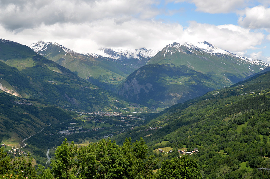 A photograph of Montchavin surrounded by mountains, fields and woods.