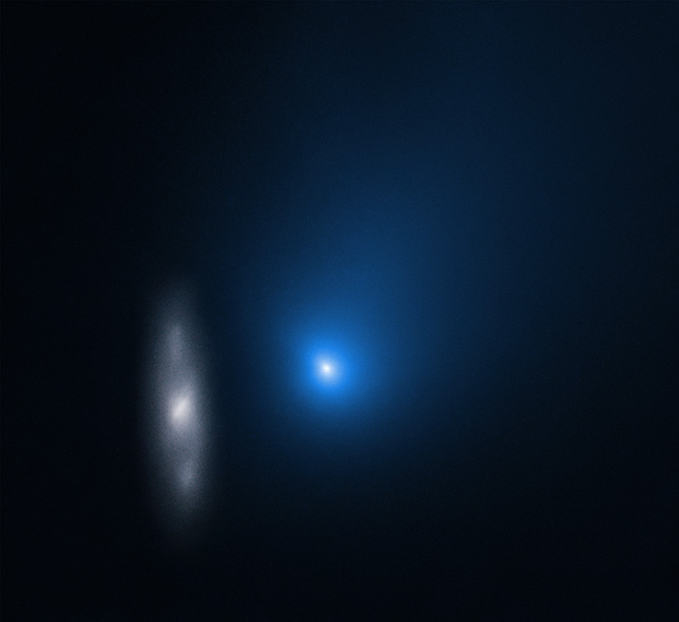 A fuzzy blue dot with a white center with a faint grayish galaxy to its left against a black background.