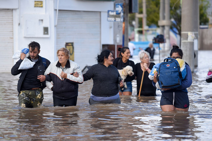 Flooding in Bahia Blanca Photograph of people walking through a flooded street with water up to their thighs.