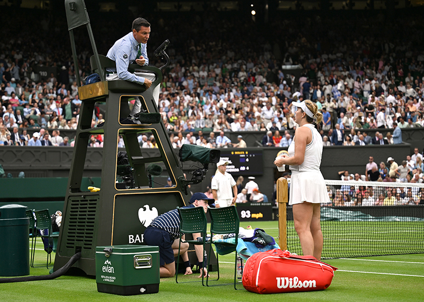 Hawk-Eye misses the call A tennis player on the ground converses with an umpire on a high chair.