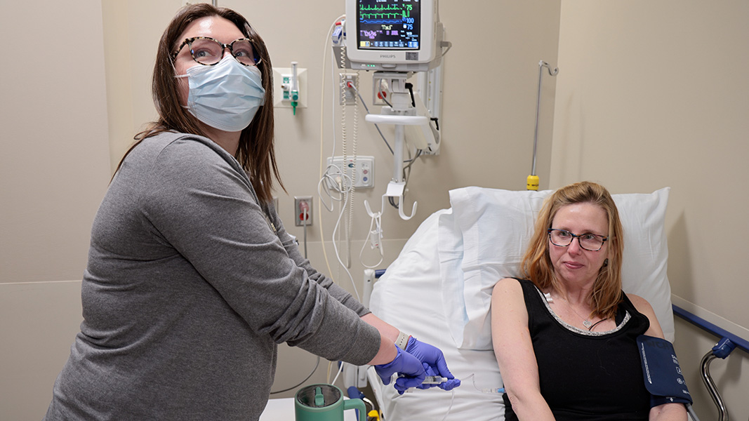 A woman in a hospital bed is receiving an infusion